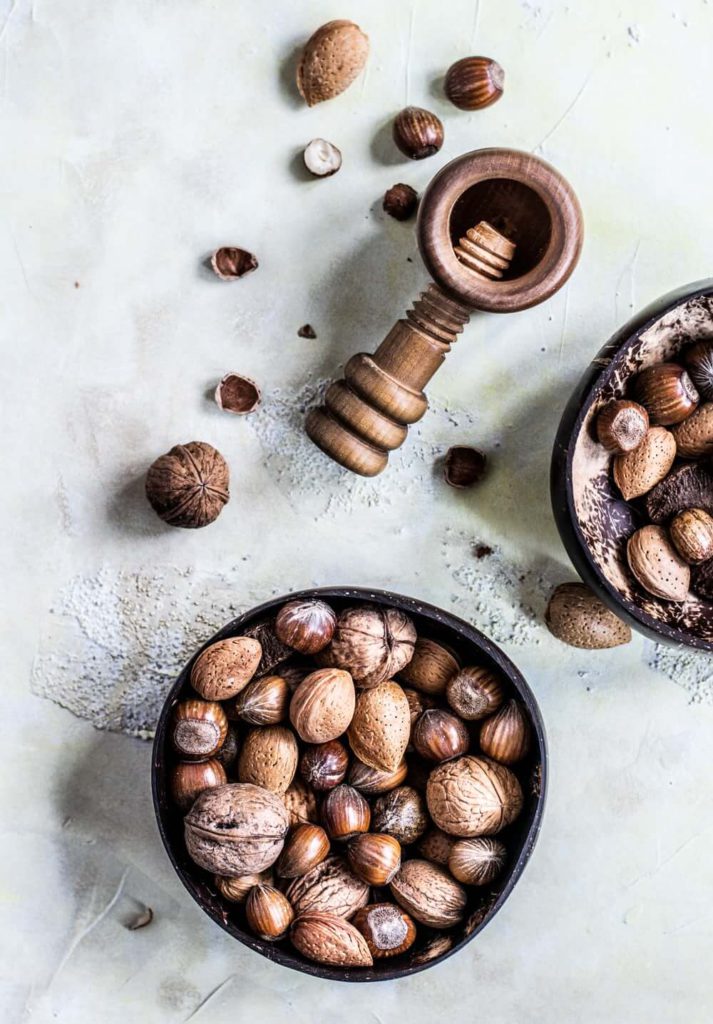 arial shot of walnuts in a bowl next to a walnut cracker and shells.