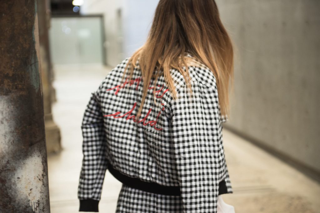 Girl with blonde hair facing away from the camera, wearing a black and white gingham coord set.